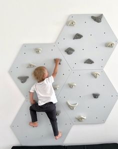 a little boy climbing up the side of a wall with rocks on it's sides