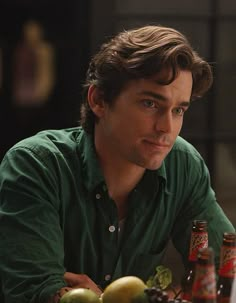 a man sitting at a table with two bottles of beer