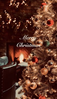 a decorated christmas tree in front of a fireplace with the words merry christmas written on it