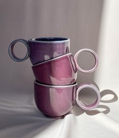 three purple mugs stacked on top of each other with their handles extended to the side