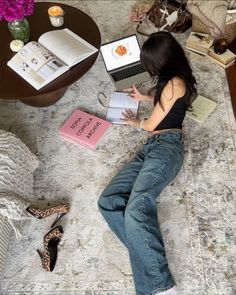 a woman is laying on the floor with her laptop and books in front of her