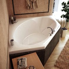 a bathroom with a large white bathtub next to a wooden table and brown rug