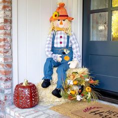 a scarecrow sitting on top of a hay bale in front of a door