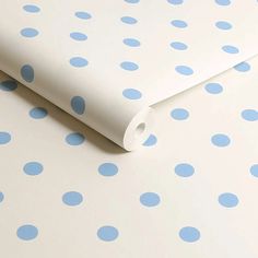 a roll of white and blue polka dot paper on top of a tablecloth with light blue dots