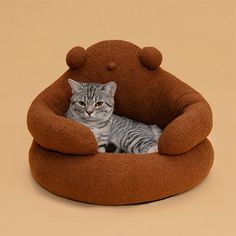 a cat sitting in a bear shaped bed on top of a brown flooring area