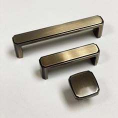 three metal handles and knobs on a white surface