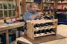 a man is looking at his cell phone in a wine shop with many bottles on the shelves