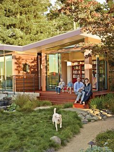 two people and a dog sitting on the porch of a small house with an open floor plan