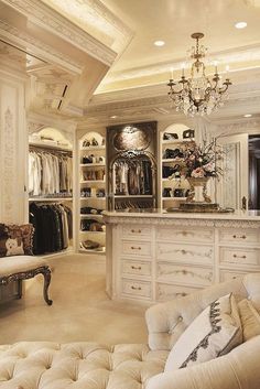 an elegant closet with white furniture and chandelier hanging from the ceiling in front of it