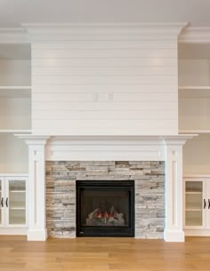 an empty living room with a fireplace and built - in bookcases