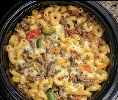 a crock pot filled with macaroni and cheese covered in ground beef sauce