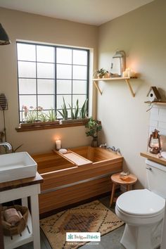 a bath room with a toilet a sink and a tub next to a large window