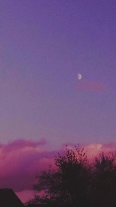 the moon is setting in the purple sky