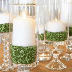 there are many candles that have been placed in glass vases with green beans on them