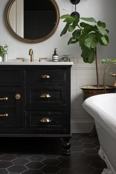 a white bath tub sitting next to a bathroom sink under a round mirror on a wall