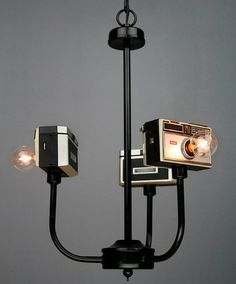 an old fashioned camera is hanging from a chandelier with two lights on it