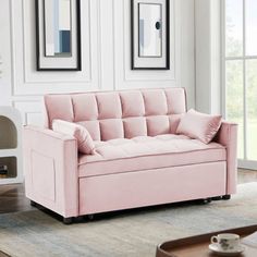 a living room with a pink couch and two framed pictures on the wall behind it