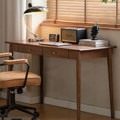 a desk with a lamp, books and other items on it in front of a window