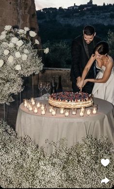 a bride and groom are cutting their wedding cake at the table with candles in front of them