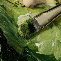 a brush is sitting on top of some green and white paint that has been painted