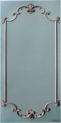 an ornate silver frame against a blue wall with white trimmings and scrolls on the edges