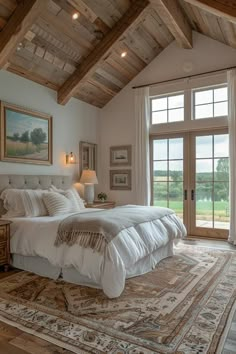 a large bed sitting under a wooden ceiling in a bedroom next to two windows with sliding glass doors