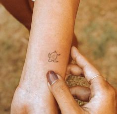 two hands holding each other with a small tattoo on their arm and wrist, both showing the outline of a turtle