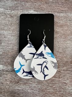 white and blue leather earrings with sharks on them, hanging from a black hook earring