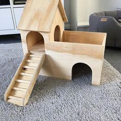 a wooden toy house with stairs to the top and bottom, sitting on carpeted floor