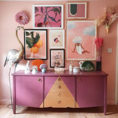 a pink dresser with pictures and flamingos on the wall