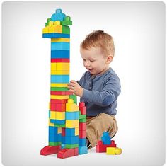 a young boy playing with a large stack of blocks