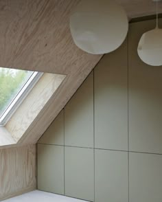 an empty room with two lamps hanging from it's ceiling and a skylight in the corner