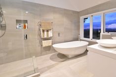 a bathroom with two sinks and a bathtub next to a large glass shower door