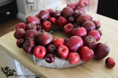 a wreath made out of apples sitting on top of a wooden table