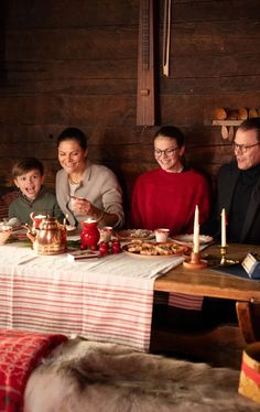 a group of people sitting at a table with food and candles in front of them