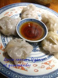 dumplings with dipping sauce on a blue and white plate sitting on a wooden table