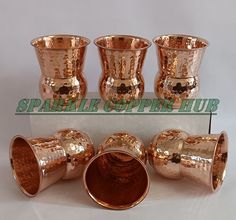 a group of copper colored cups sitting on top of a white box next to each other