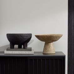 two vases sitting on top of a black cabinet