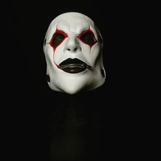 a white mask with red eyes and fangs on it's face in the dark