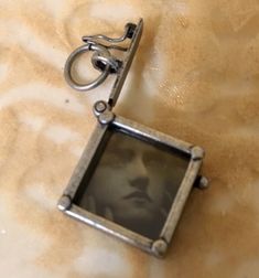 a keychain with an old photo hanging from it's side on a bed