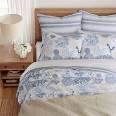 a bed with blue and white bedspread in a bedroom next to a night stand