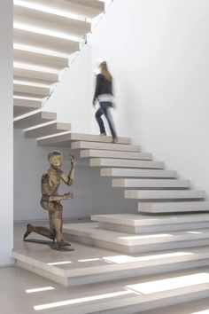 a woman standing on top of a stair case next to a statue of a boy