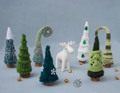 small knitted christmas trees and decorations are arranged in rows on a gray background with gold bells