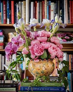 a vase filled with pink and white flowers next to books