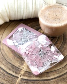 a drink sitting on top of a wooden table next to a plate with pink flowers