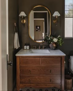 a bathroom with a sink, mirror and lights on the wall next to a toilet