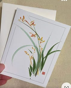 a person holding up two cards with flowers on them, one is white and the other is yellow