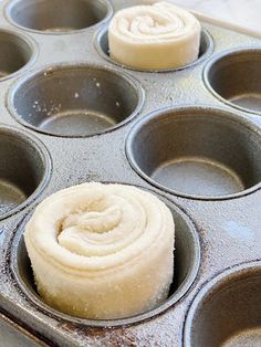 a muffin pan filled with cupcakes covered in frosting and rolled up