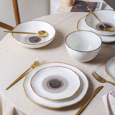 a table topped with white plates and goldware