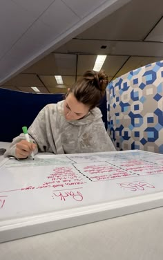 a woman writing on a large white board